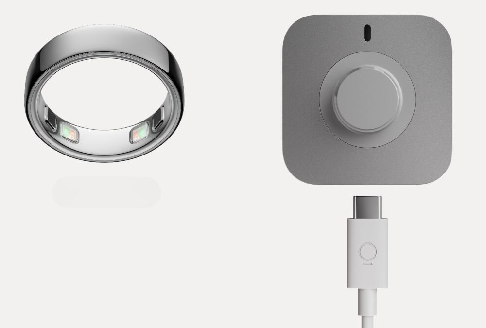 Na obrazie widoczny jest czarny pierścień oraz szara ładowarka z okrągłym elementem i kablem USB-C.