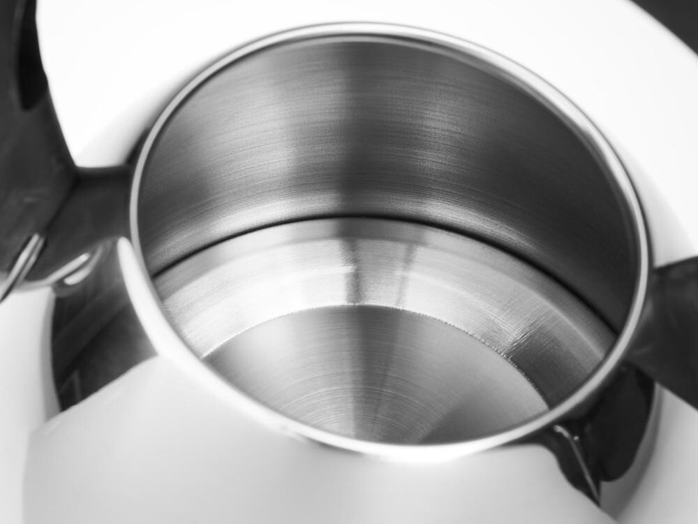 Wnętrze stalowego czajnika z widocznym połyskiem metalu. Krawędzie są gładkie, a powierzchnia ma delikatne, okrągłe wzory.