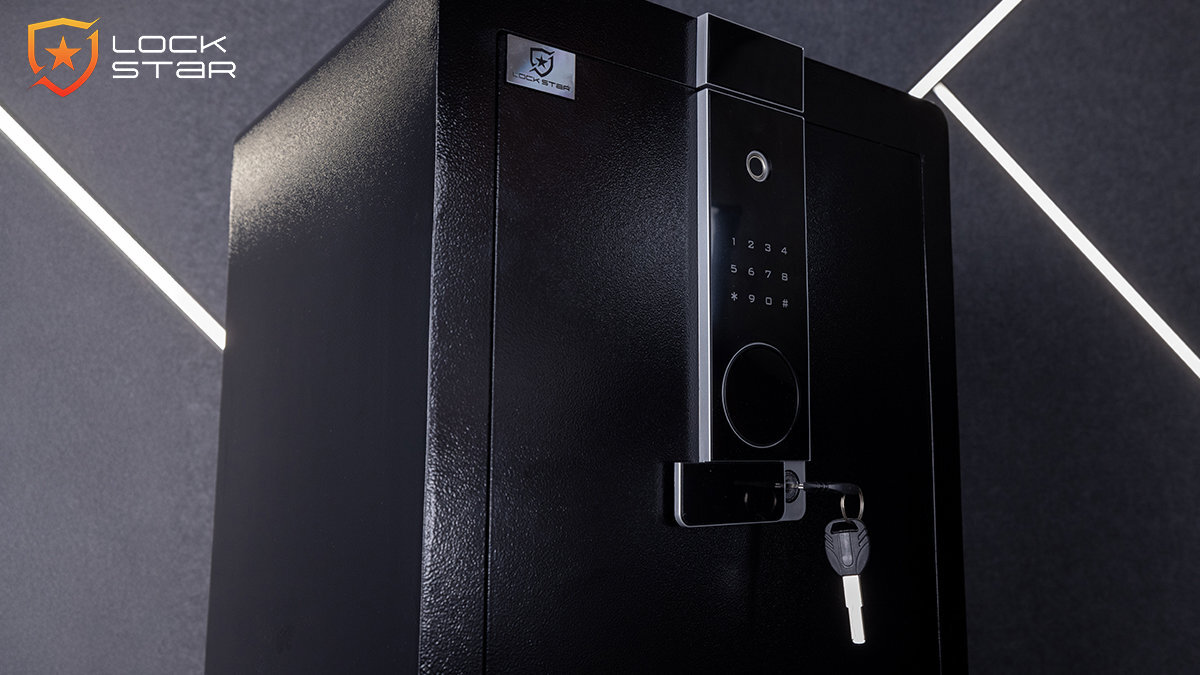 Czarny sejf z elektronicznym panelem z klawiaturą numeryczną i miejscem na klucz. Widoczne logo \'LOCK STAR\' w lewym górnym rogu obrazu.