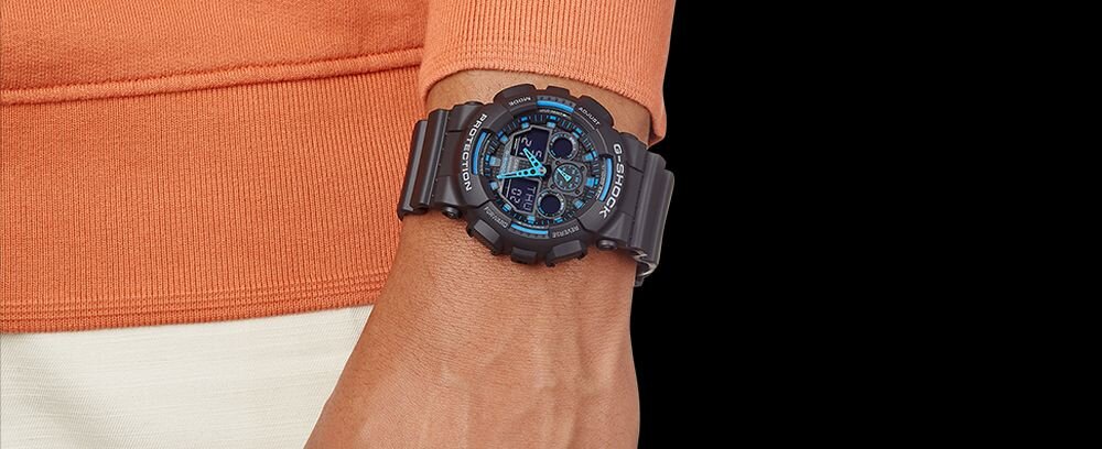 Osoba nosi czarno-niebieski zegarek sportowy na nadgarstku. Zegarek ma widoczne logo \'G-SHOCK\' na tarczy.