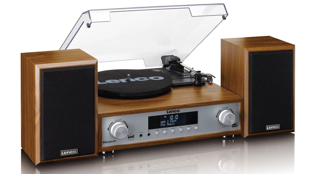 Gramofon w drewnianej obudowie z przezroczystą pokrywą, wyposażony w dwa głośniki. Na panelu przednim widoczne są pokrętła, wyświetlacz oraz logo Lenco.