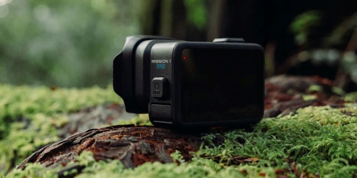 Kamera GoPro Mission 1 leżąca na mchu przy ściółce leśnej.