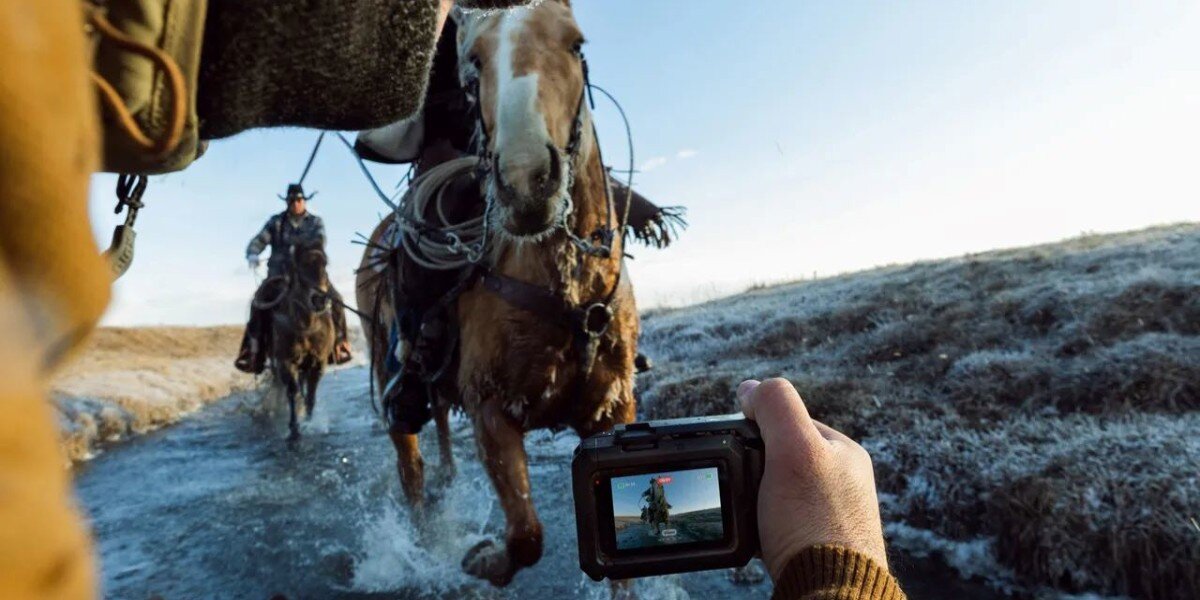 Osoba nagrywająca biegnące konie kamerą GOPRO Mission 1 Pro.