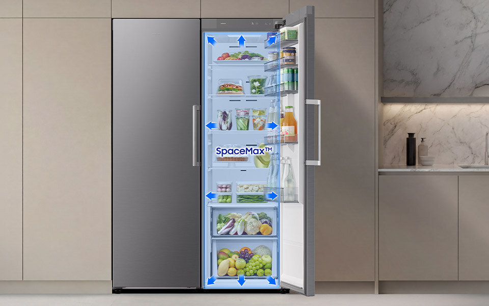 Większa pojemność Otwarta lodówka z widocznymi półkami wypełnionymi różnorodnymi produktami spożywczymi. Na drzwiach lodówki widoczny jest napis \'SpaceMax™\'.