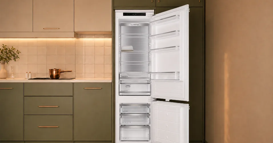 Wnętrze otwartej lodówki z widocznymi półkami i szufladami. Na drzwiach lodówki widoczny jest napis \'Total No Frost\' oraz \'Vegetable\'.