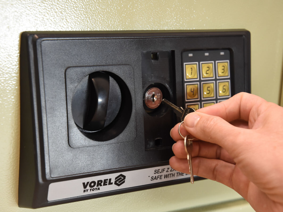 Sejf VOREL 78642, diody, kontrolki, zamek, zablokowanie, dłoń wkłada klucz do zamka manualnego sejfu