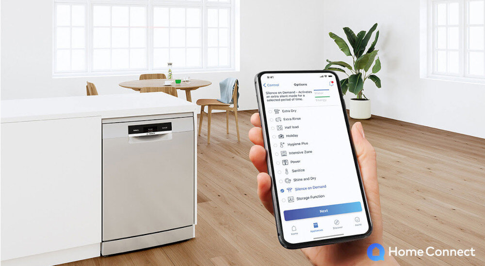 W jasnej kuchni znajduje się zmywarka z panelem sterowania, obok której osoba trzyma smartfon z aplikacją Home Connect. Na ekranie telefonu widoczne są opcje zmywania, takie jak \'Extra Dry\', \'Extra Rinse\', \'Half Load\', \'Hygiene Plus\', \'Intensive Zone\', \'Power\', \'Speed\', \'Shine and Dry\', \'Silence on Demand\', \'Storage Function\'.