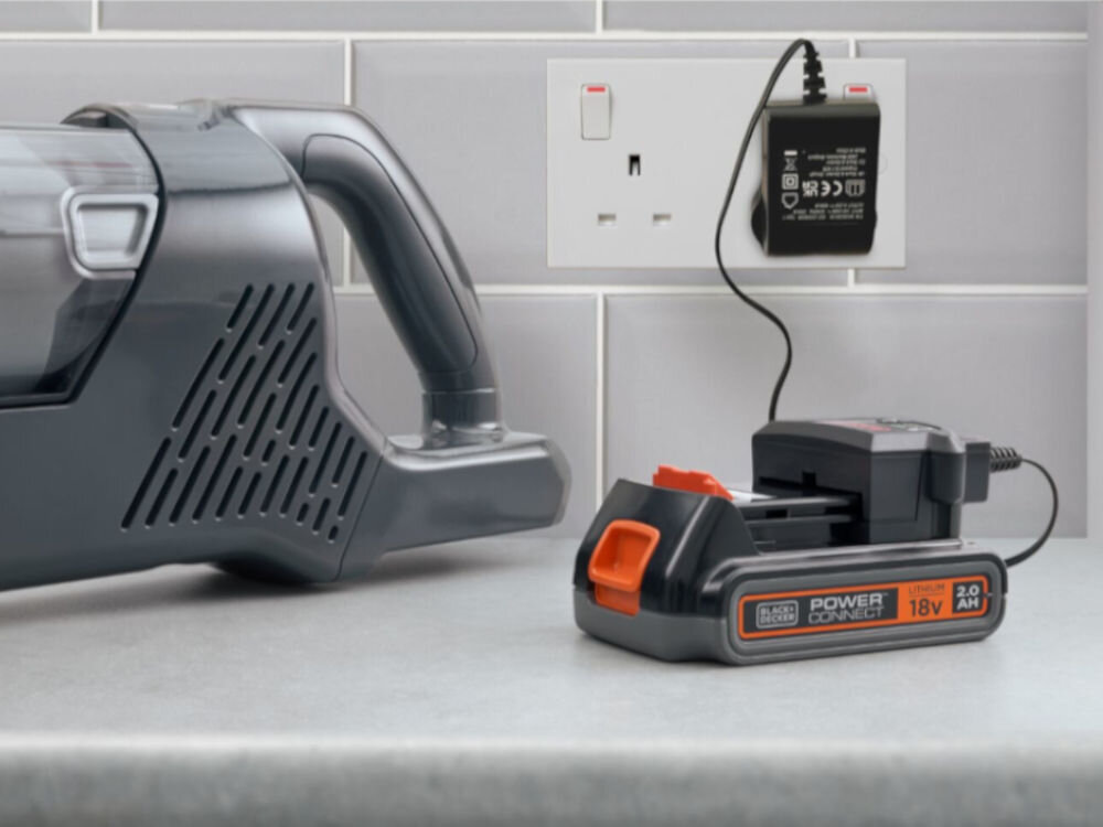 Akumulator BLACK&DECKER BL2018-XJ 2Ah 18V, współpraca, wielozadaniowość, różne urządzenia, Akumulator leży na blacie w kuchni, podłączony do kontaktu, obok leży kompatybilny sprzęt