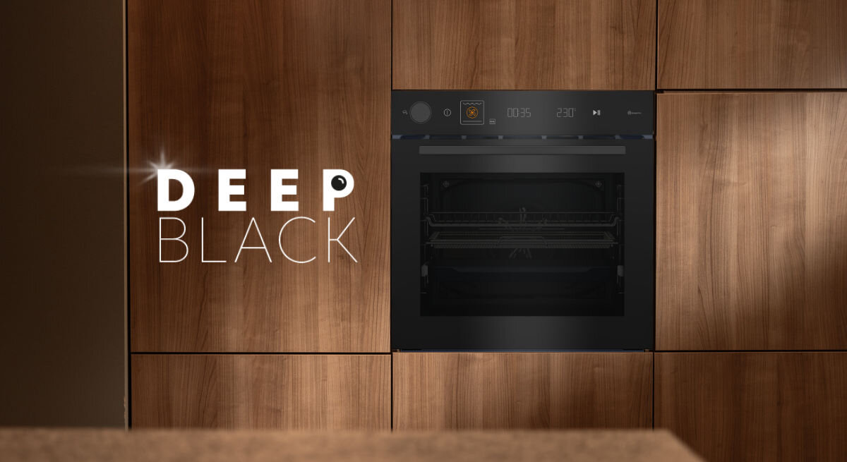 Czarny piekarnik wbudowany w drewnianą zabudowę kuchenną, obok napis \'DEEP BLACK\'.