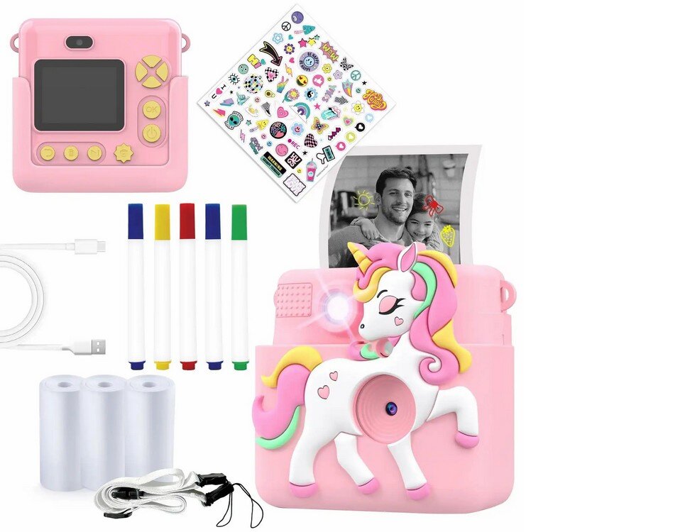 Na obrazie widoczny jest różowy aparat natychmiastowy z motywem jednorożca, obok którego znajdują się kolorowe markery, naklejki, kabel USB, trzy rolki papieru oraz przewód. Aparat ma wyświetlacz i przyciski w kolorze żółtym, a z jego wnętrza wystaje czarno-białe zdjęcie przedstawiające dwie osoby.