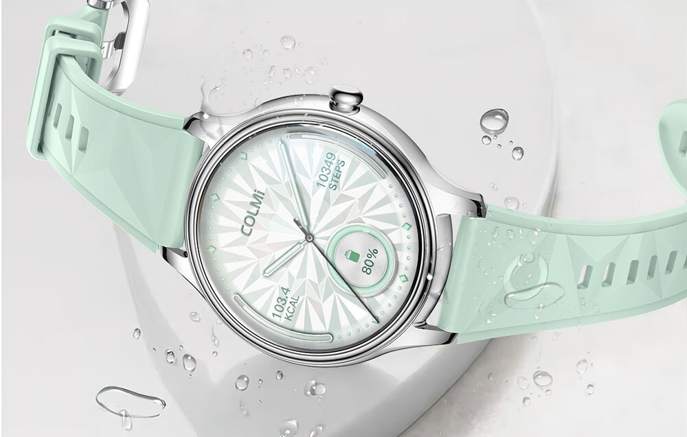Smartwatch z okrągłą tarczą i miętowym paskiem, na której widoczny jest tekst: \'COLMI\', \'10349 STEPS\', \'10.4 KCAL\', \'80%\'. Tło jest jasne z kroplami wody.