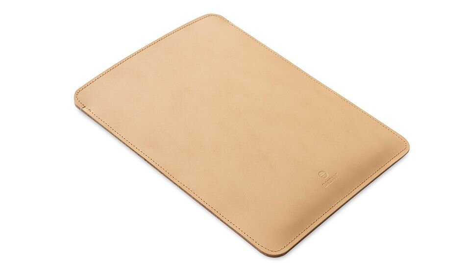 Beżowe etui na laptopa o prostokątnym kształcie z zaokrąglonymi rogami, wykonane z gładkiego materiału. Na powierzchni widoczne jest subtelne logo producenta.
