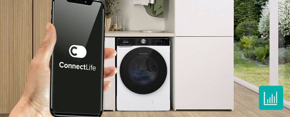 Osoba trzyma smartfon z aplikacją ConnectLife na ekranie. W tle znajduje się biała suszarka z czarnym panelem, ustawiona w nowoczesnym wnętrzu z widokiem na ogród.