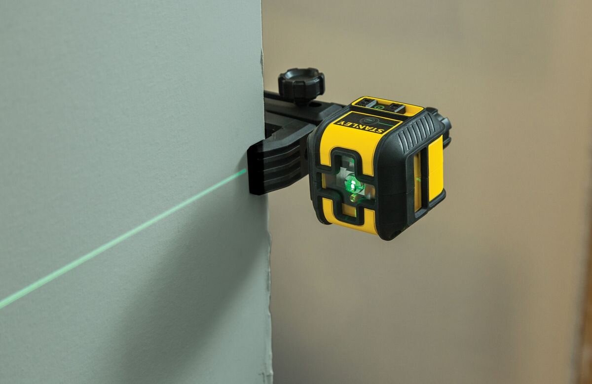 Laser krzyżowy STANLEY CROSS90 STHT77592-1, przycisk, obsługa, prosta, praca, laser odmierza linie na ścianie, zamontowany do uchwytu
