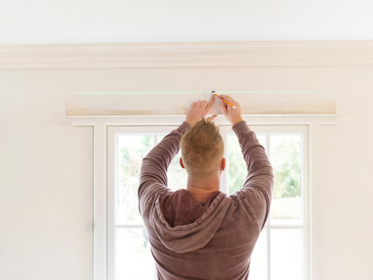 Laser krzyżowy STANLEY CROSS90 STHT77592-1, zasięg, laser, światło, widoczność, mężczyzna odmierza laserem wymiary nad oknem