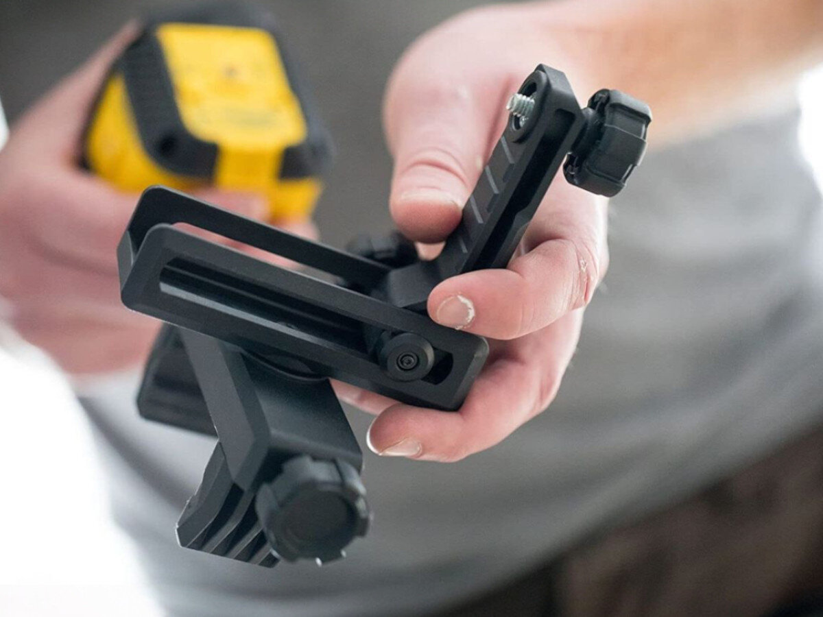 Laser krzyżowy STANLEY Cubix STHT77499-1, bateria, praca, czas, energia, Uchwyt QuickLink zamocowany na drewnianym boku.