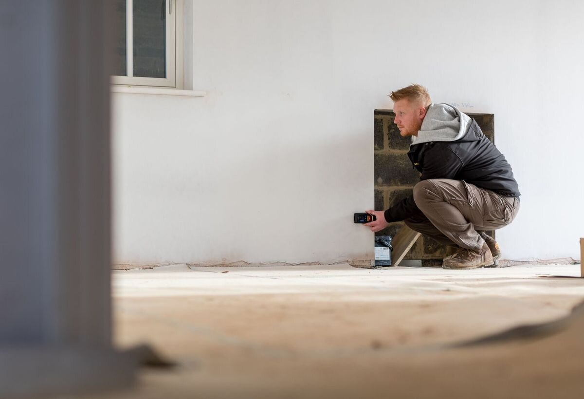 Dalmierz laserowy STANLEY TLM 165S STHT1-77139 50m, laser, odległość, precyzja, zasięg, mężczyzna odmierza laserem dystans w remontowanym pomieszczeniu