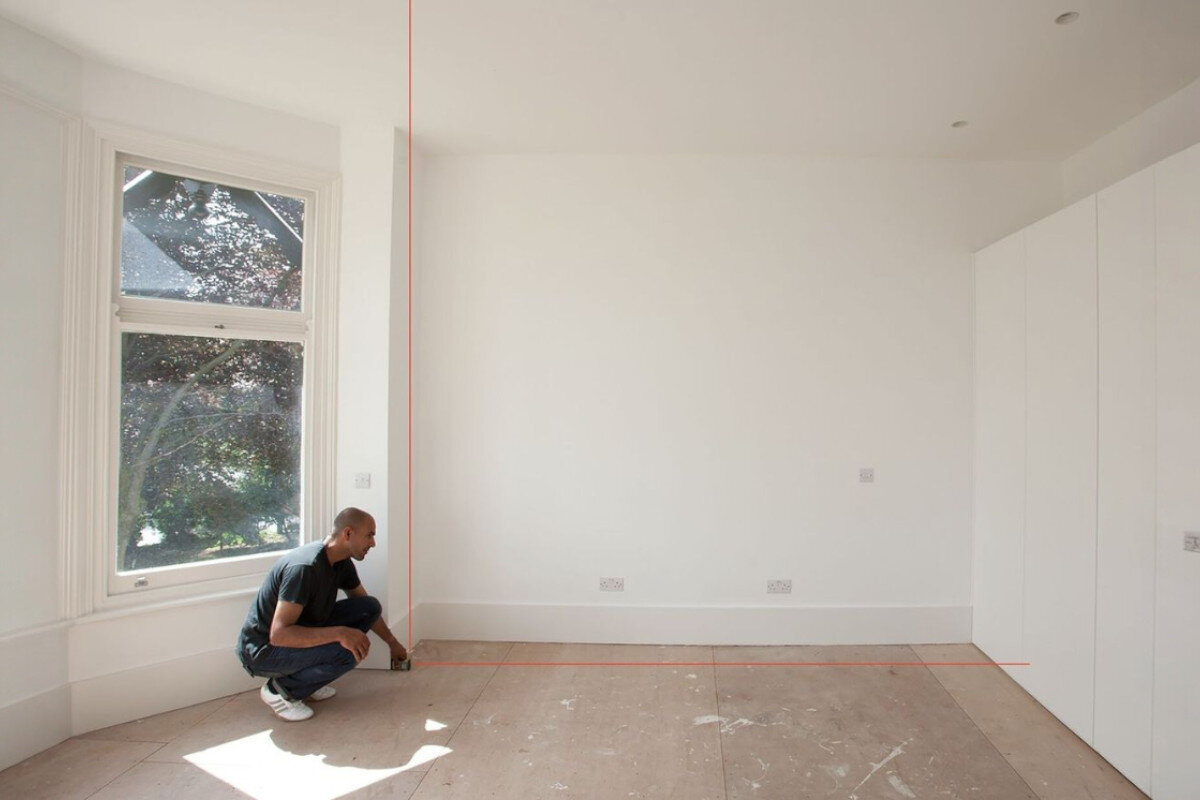 Dalmierz laserowy STANLEY TLM 165S STHT1-77139 50m, wysokość, powierzchnia, objętość, jednostki, mężczyzna odmierza laserem dystans w remontowanym pomieszczeniu