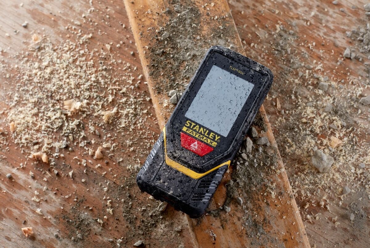 Dalmierz laserowy STANLEY TLM 165S STHT1-77139 50m, ochrona, kurz, budowa, trwałość, dalmierz leży w trocinach na podłodze deskowanej