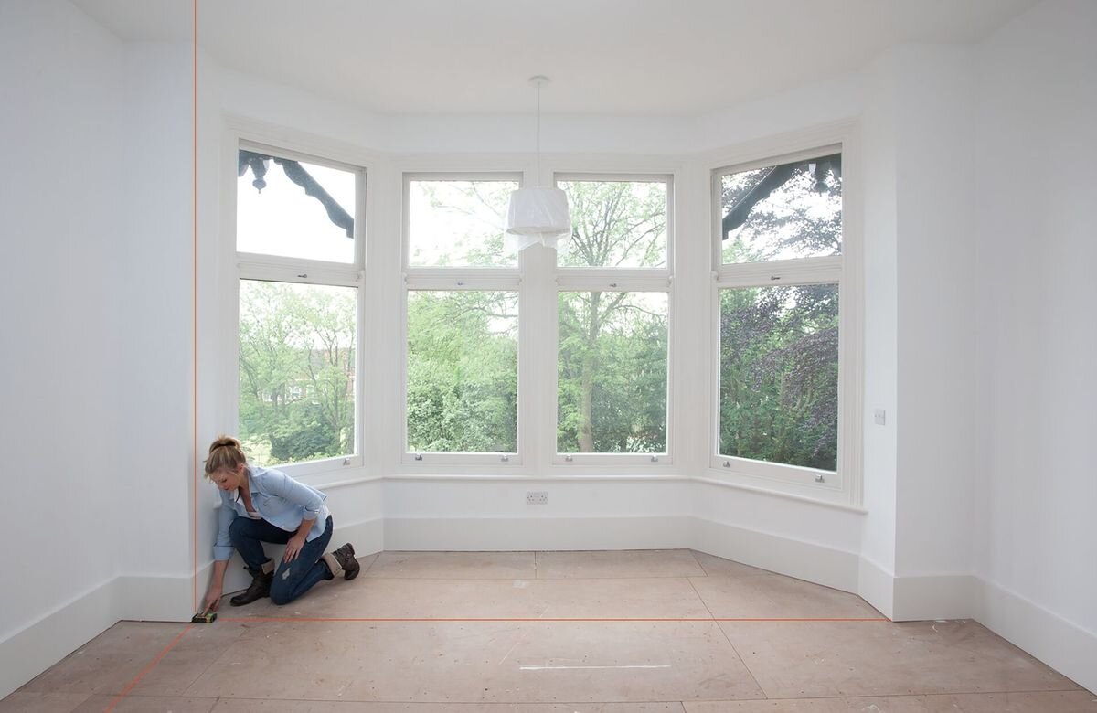 Dalmierz laserowy STANLEY TLM 165S STHT1-77139 50m, Bluetooth, aplikacja, transfer, archiwum, kobieta odmierza laserem dystans w remontowanym pomieszczeniu