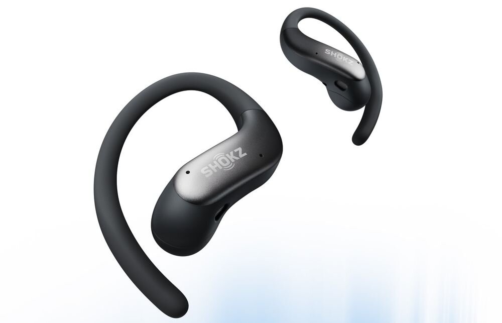 Na obrazie widoczne są czarne słuchawki powietrzne z logo \'SHOKZ\' na obudowie. Słuchawki mają zakrzywiony kształt, umożliwiający dopasowanie do ucha.