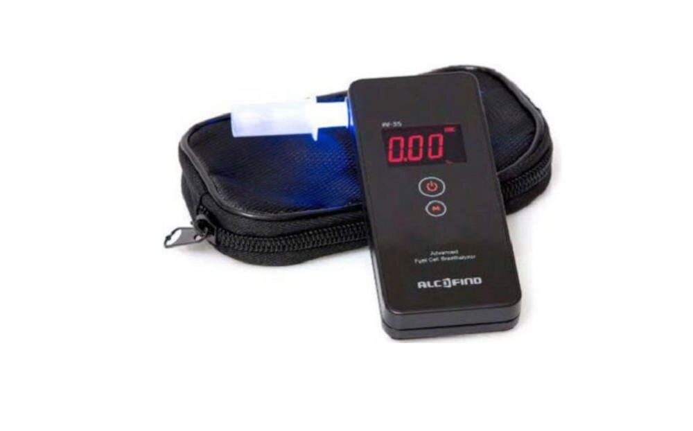 Na obrazie widoczny jest alkomat z wyświetlaczem pokazującym \'0.00\' oraz etui. Na urządzeniu znajduje się napis \'ALCOFIND\'.