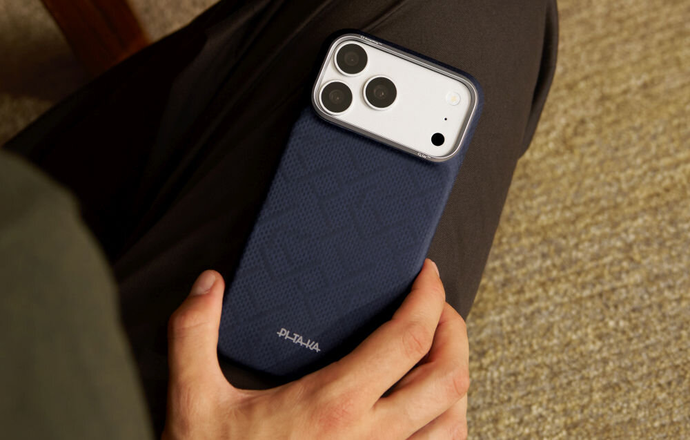 Osoba trzyma telefon w niebieskim etui z widocznym logo \'PITAKA\'.