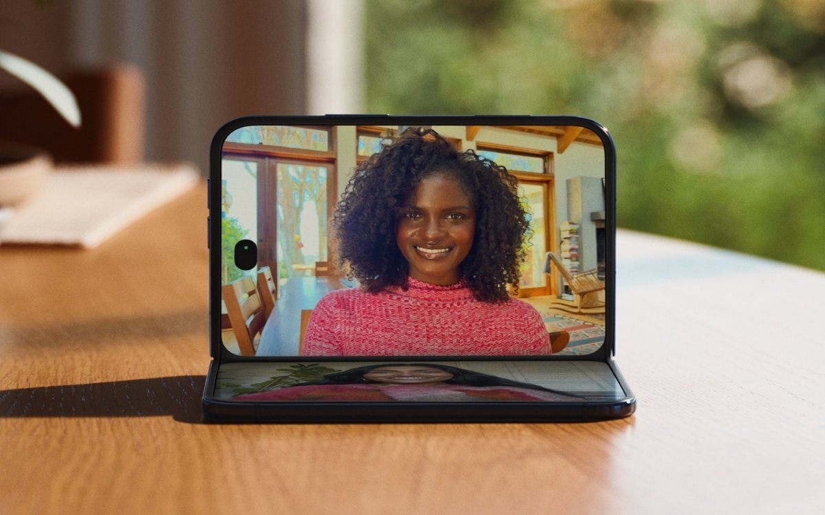 Smartfon iPhone Duo ustawiony na drewnianym stole, ne ekranie widoczna jest rozmowa dwóch osób.