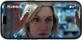 Smartfon wyświetla scenę z filmu, na której widoczna jest kobieta z blond włosami. Na ekranie widoczne są napisy \'PLURIBUS\' i logo \'tv\'.