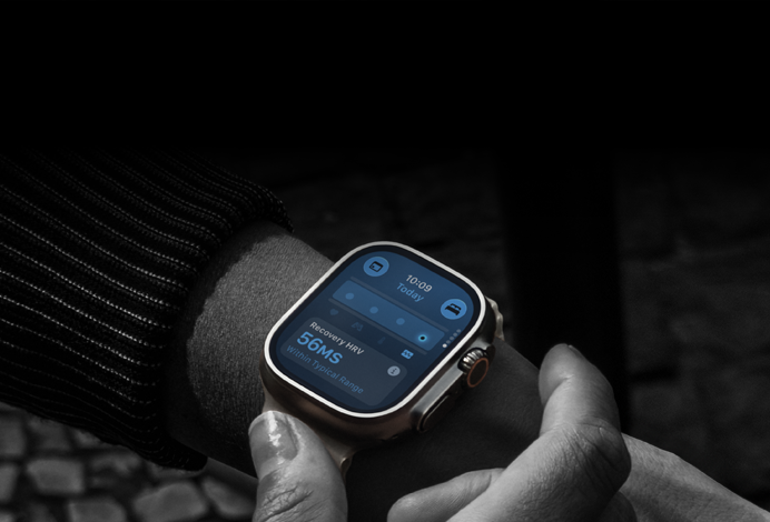 Osoba nosi smartwatch z prostokątnym ekranem, na którym wyświetlane są dane dotyczące zdrowia, w tym \'Recovery HRV 56MS Within Typical Range\'.