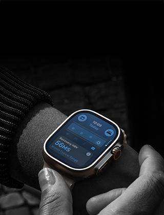 Osoba nosi smartwatch z prostokątnym ekranem, na którym wyświetlane są informacje o pogodzie i ciśnieniu. Zegarek ma metalową kopertę i ciemną bransoletę.