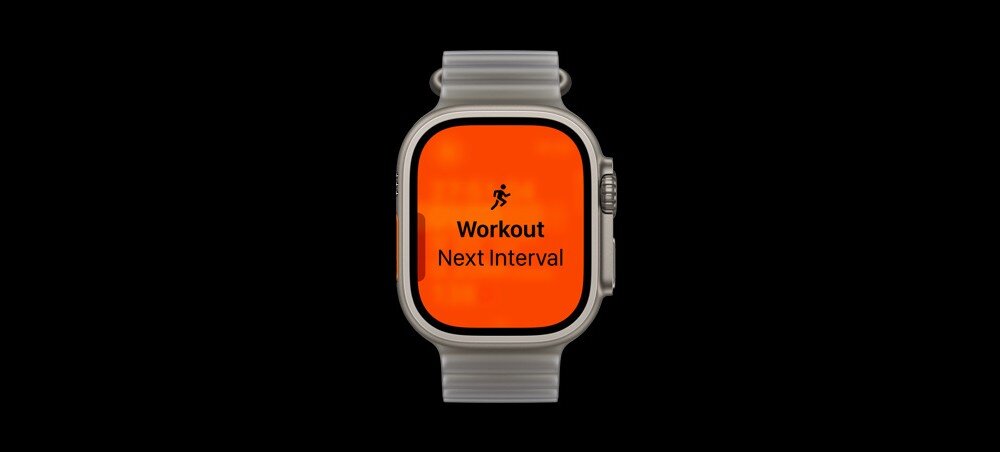 Zegarek z pomarańczowym ekranem wyświetlającym tekst: \'Workout Next Interval\'.
