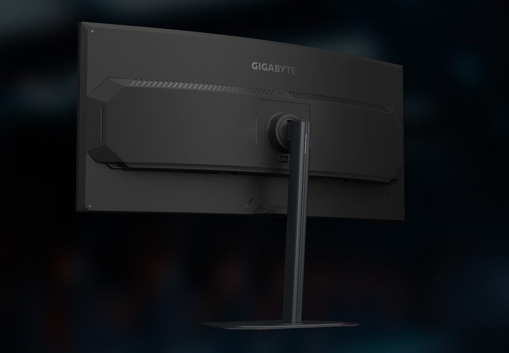 Monitor z zakrzywionym ekranem widoczny od tyłu, z logo GIGABYTE na obudowie. Monitor jest zamontowany na prostokątnej podstawie.