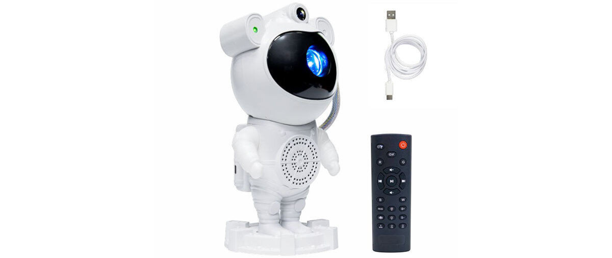 Na obrazie znajduje się biały projektor w kształcie astronauty z niebieskim światłem na przodzie, obok czarny pilot z przyciskami oraz biały kabel USB.