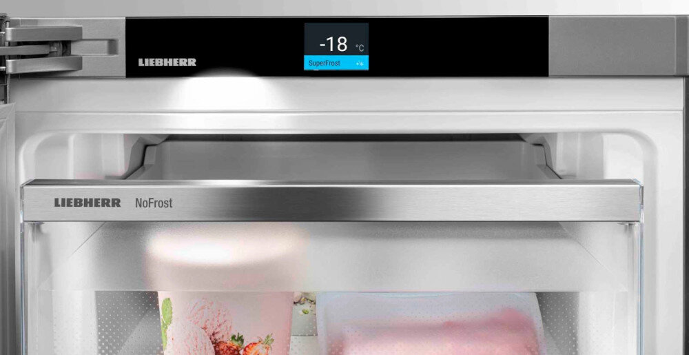 Wnętrze lodówki z widocznym wyświetlaczem pokazującym temperaturę -18°C i funkcję SuperFrost. Na drzwiach i szufladzie widoczne jest logo LIEBHERR oraz napis NoFrost.