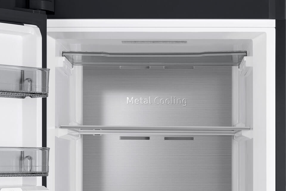 Wnętrze lodówki z metalowym panelem i napisem \'Metal Cooling\'. Widoczne są dwie półki oraz boczne pojemniki na drzwiach.