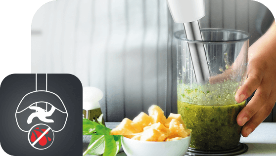 Na obrazie widać blender zanurzeniowy miksujący zieloną masę w wysokim naczyniu, obok znajdują się kawałki żółtych owoców. W lewym dolnym rogu jest ikona przedstawiająca ostrze z przekreślonym symbolem owocu.