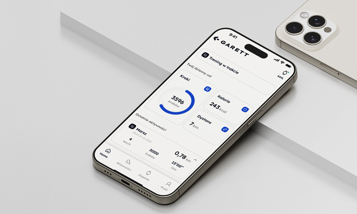 Na obrazie widoczny jest smartfon z aplikacją fitness, na której widać dane dotyczące kroków, kalorii i dystansu. W tle znajduje się inny smartfon z trzema obiektywami aparatu.
