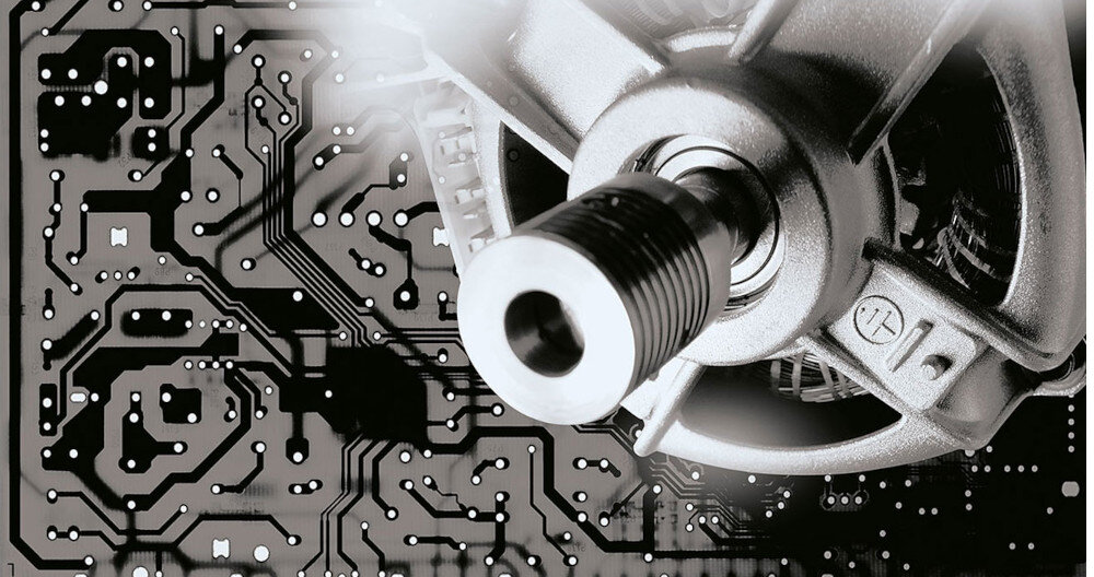 Obraz przedstawia zbliżenie na metalowy element mechaniczny na tle płytki drukowanej z widocznymi ścieżkami i punktami lutowniczymi.