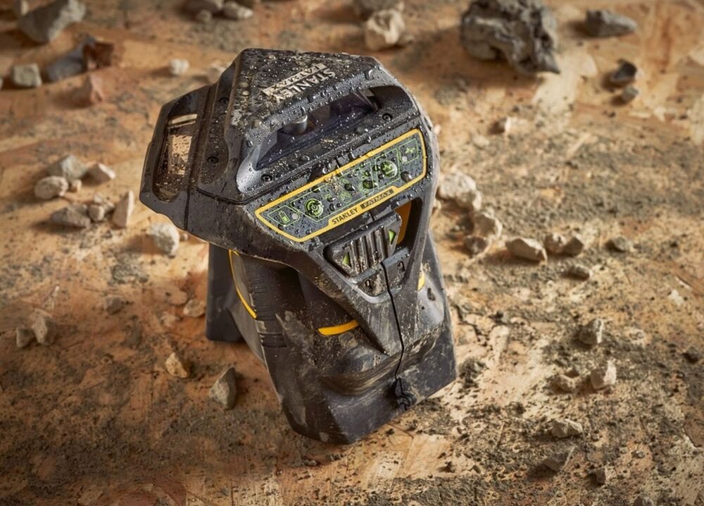 Laser krzyżowy STANLEY FatMax Multi-Line Laser 360, obudowa, kurz, woda, trwałość, laser stoi na ziemi brudny od trocin i ziemi