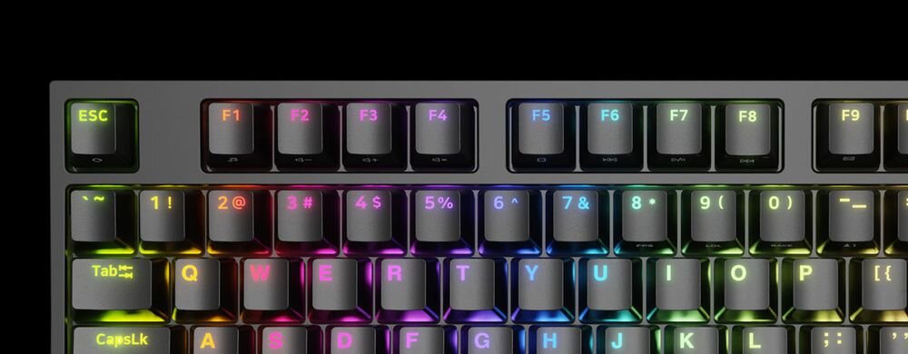 Klawiatura mechaniczna z podświetleniem RGB, widoczne klawisze funkcyjne F1-F9 oraz klawisze alfanumeryczne z różnokolorowym podświetleniem. Klawisz ESC jest podświetlony na zielono, a klawisze Tab i CapsLk mają żółte podświetlenie.