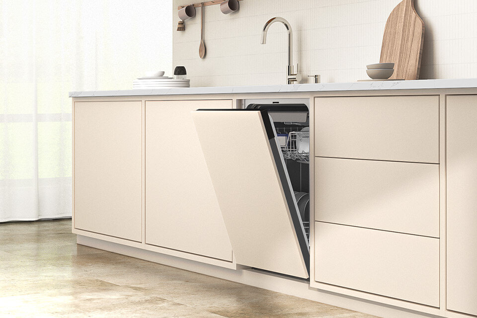Zmywarka do pełnej zabudowy Samsung DW50DG451B00ET o szerokości 45 cm z oferty Media Expert Kuchnia z jasnymi szafkami, w której znajduje się otwarta zmywarka w zabudowie. Na blacie widoczne są naczynia, zlew i drewniana deska do krojenia.