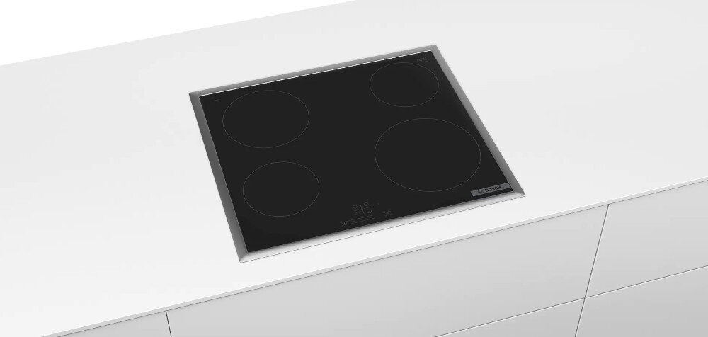 Czarna płyta ceramiczna z czterema okrągłymi polami grzewczymi, zamontowana na białym blacie kuchennym. Widoczne jest logo \'BOSCH\'.