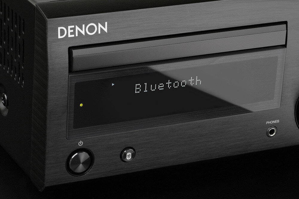 Czarny amplituner stereo z wyświetlaczem pokazującym tekst \'Bluetooth\'. Na obudowie widoczne jest logo \'DENON\'.