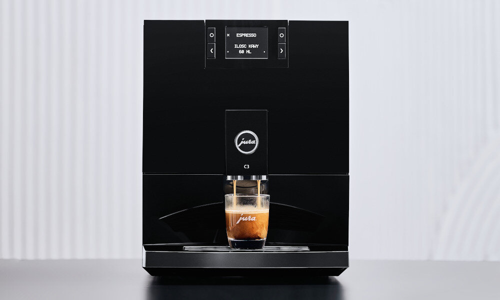 Czarny ekspres do kawy z logo \'jura\' na przednim panelu, przygotowujący filiżankę kawy. Na wyświetlaczu widoczny jest tekst: \'ESPRESSO ILOŚĆ WODY 60 ML\'.