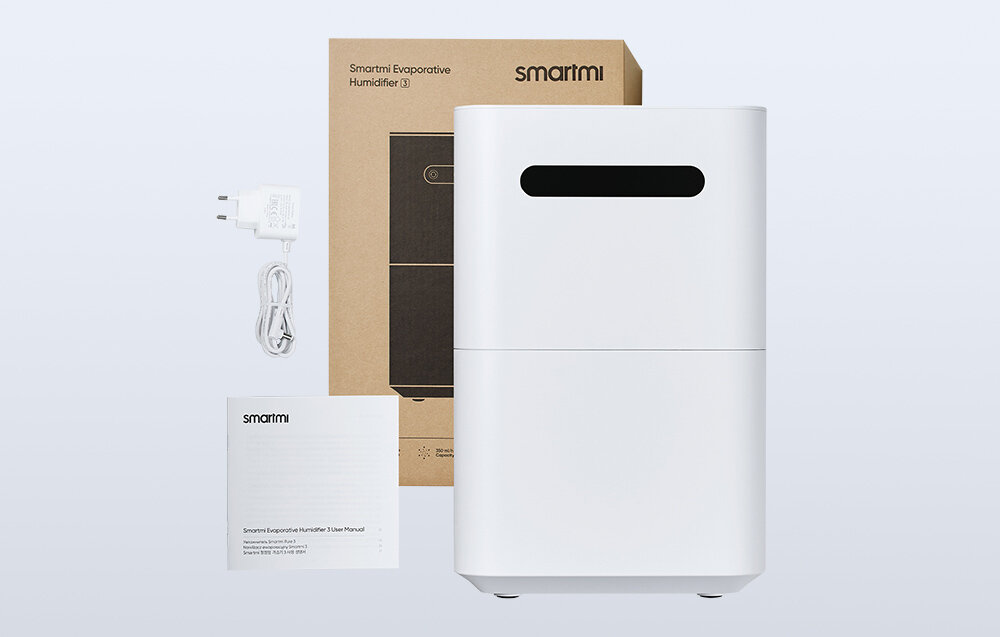 Na obrazie znajduje się biały nawilżacz powietrza z czarnym panelem, obok którego leży instrukcja obsługi, kabel zasilający oraz pudełko z napisem \'Smartmi Evaporative Humidifier (3)\'.