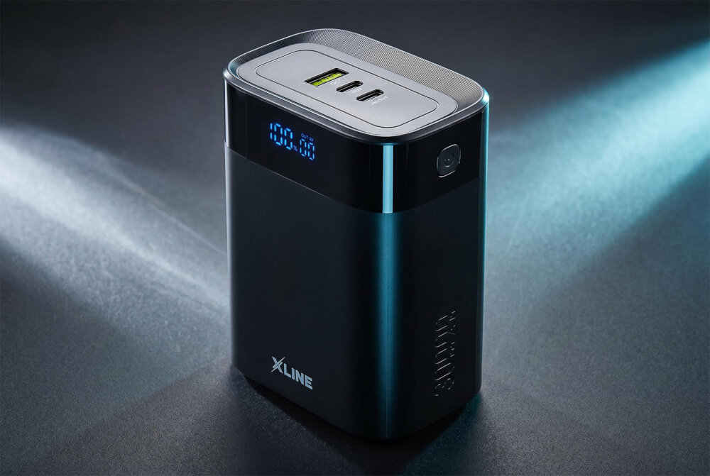 Czarny powerbank z logo XLINE, posiadający wyświetlacz LED pokazujący \'100.00\' oraz trzy porty na górze. Obok znajduje się przycisk, a całość jest oświetlona z boku.