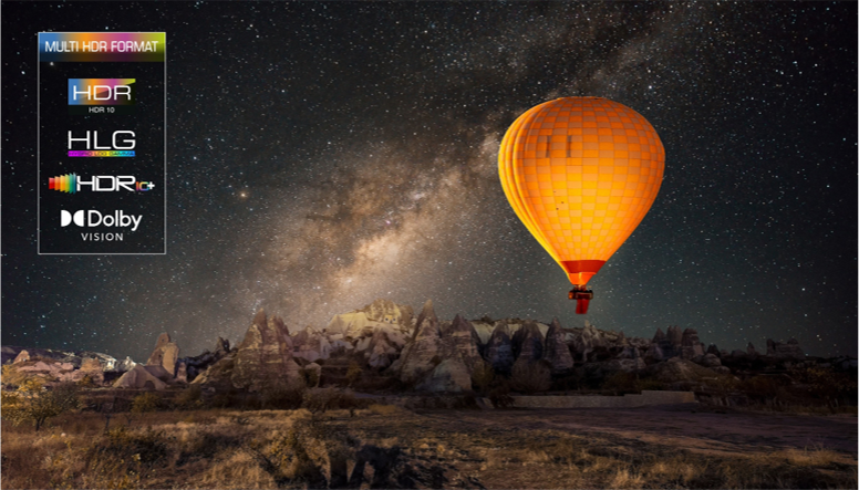 Na nocnym niebie widać pomarańczowy balon unoszący się nad skalistym krajobrazem. Po lewej stronie obrazu znajdują się logotypy: \'MULTI HDR FORMAT\', \'HDR HDR 10\', \'HLG\', \'HDR10+\', \'Dolby VISION\'.