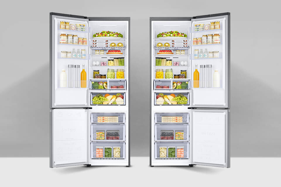 rb38c675cs9 przekładane drzwi Dwie otwarte lodówki wypełnione różnorodnymi produktami spożywczymi, takimi jak owoce, warzywa, napoje i słoiki. Lodówki mają srebrne wykończenie i są ustawione na szarym tle.