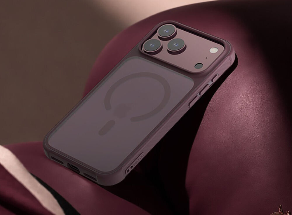 Fioletowe etui na telefon z trzema widocznymi aparatami i okrągłym wzorem na tylnej części. Etui leży na ciemnoczerwonym tle.